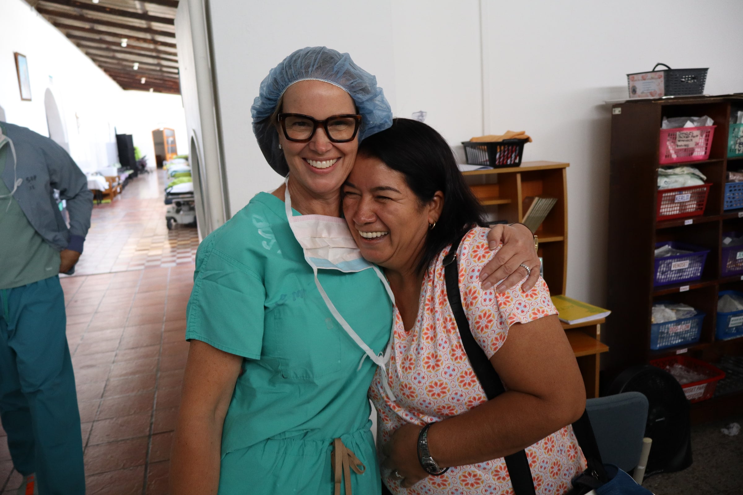 A patient and a team member embrace and smile in a hospital corridor.