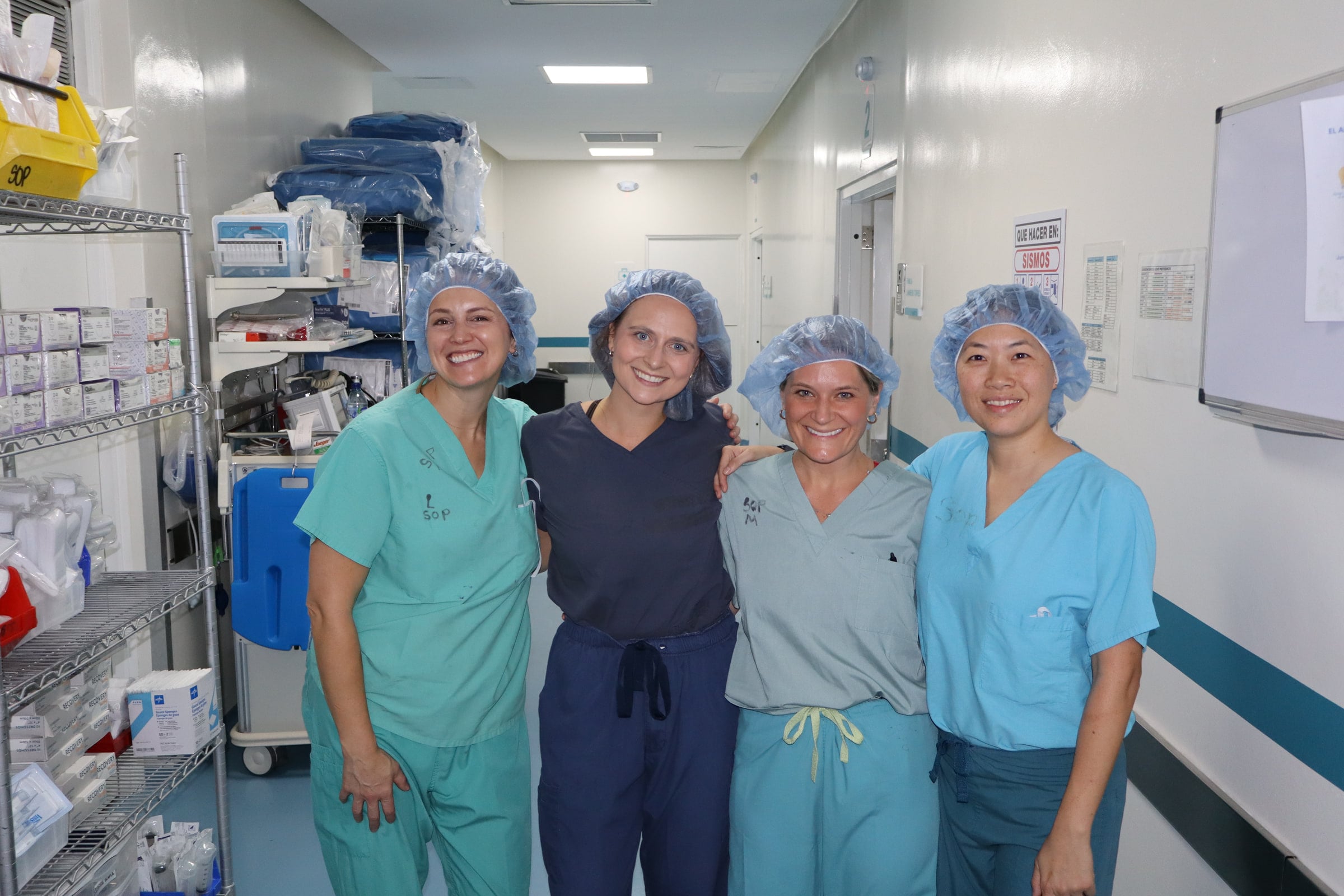 Four team members in scrubs stand together in a supply corridor.