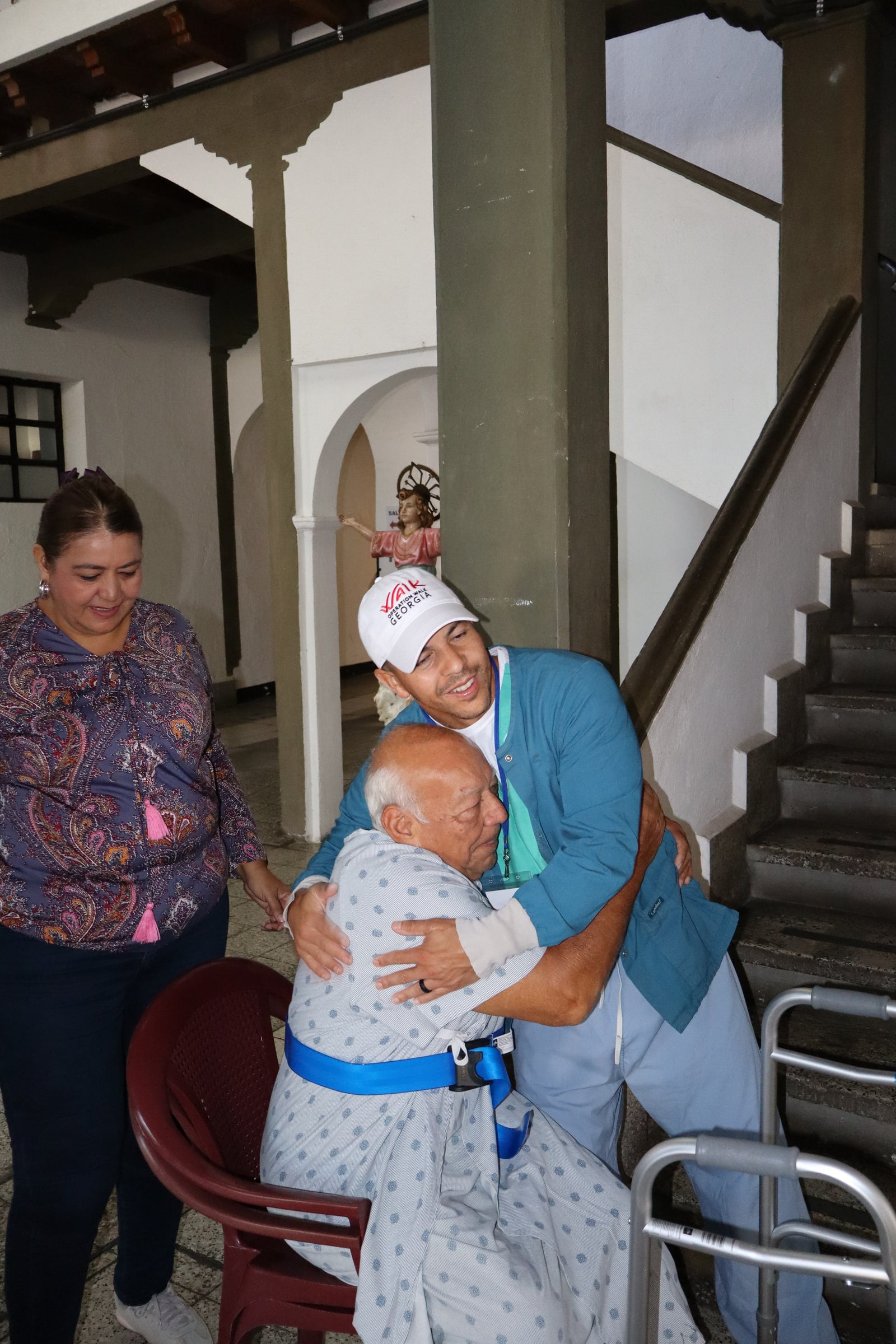 A patient embraces a team member near the hospital stairs.