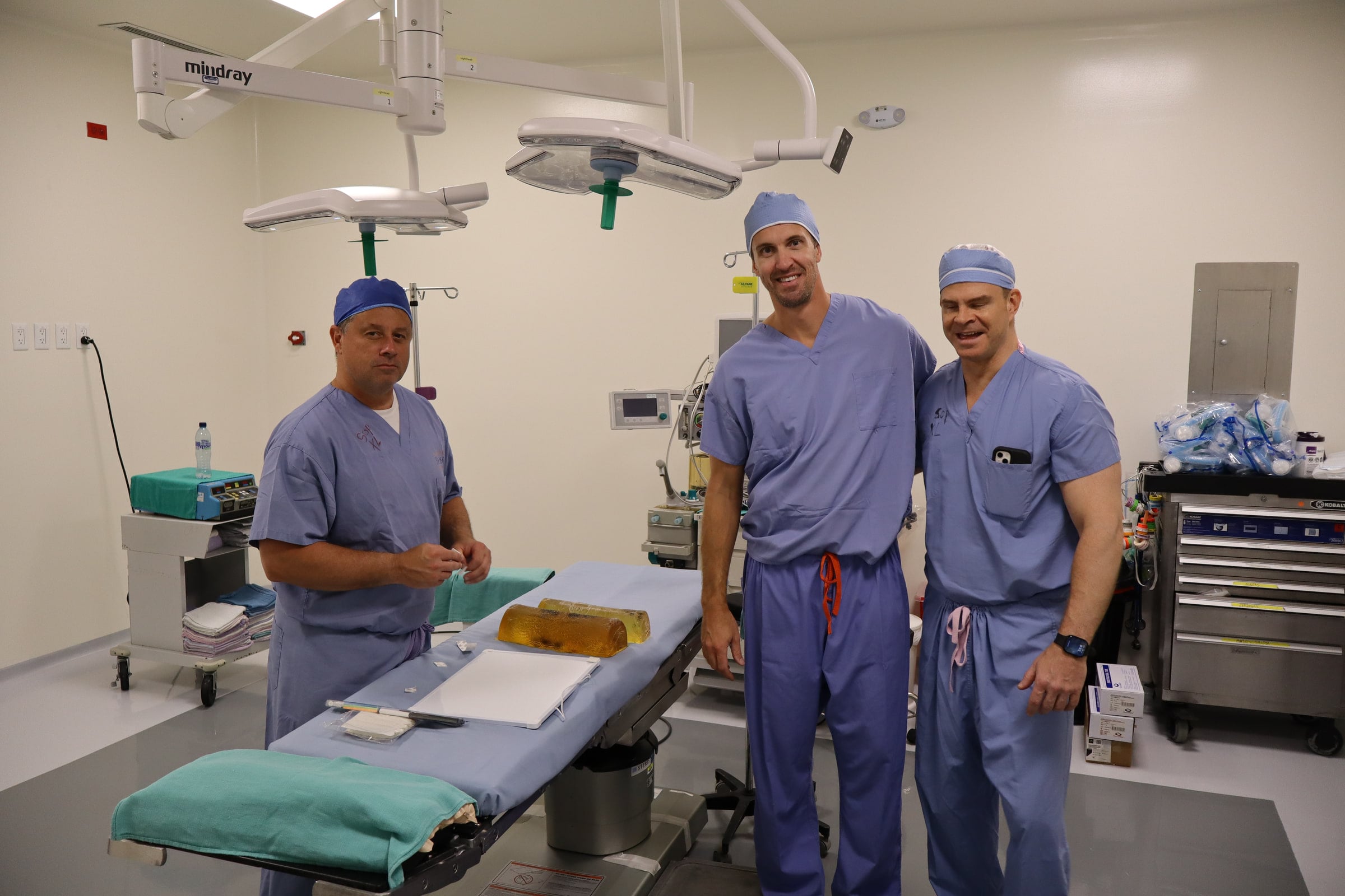 Masked team members stand together in an operating room.